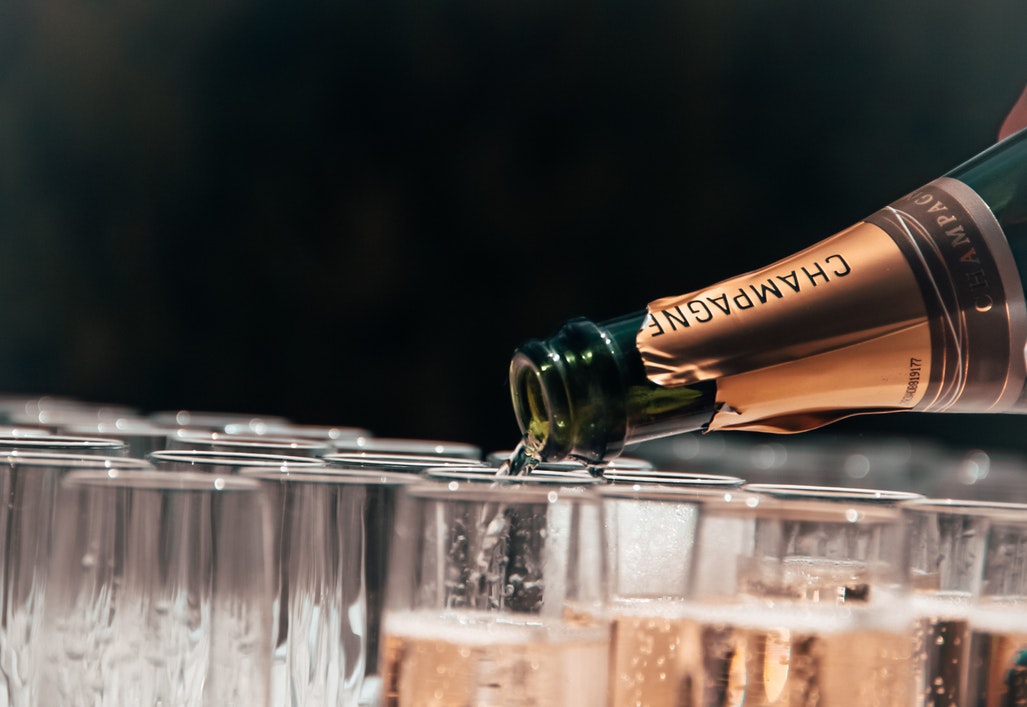 Champagne being poured into a row of flutes